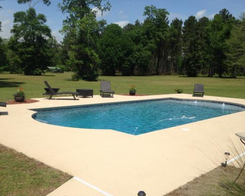 Adel custom pool design with luxury stone deck and blue water.