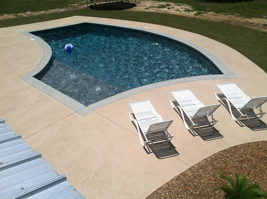 Aerial view of Mystic Pools remodeled freeform gunite pool in Moultrie with dark finish, updated coping, wide concrete pool deck, white lounge chairs, and automatic pool cover