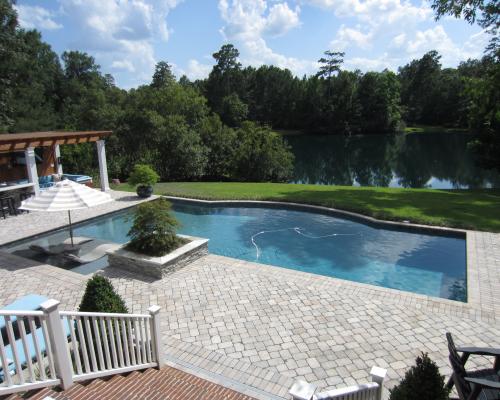 Adel swimming pool construction with blue water, stone deck, and luxury finishes.