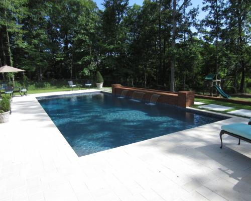 Quitman swimming pool construction with custom pool shape and stone decking.